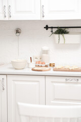 Home kitchen interior.Bowl with dough and spatula, eggs and bowl of sugar, napkin on kitchen table in modern kitchen.