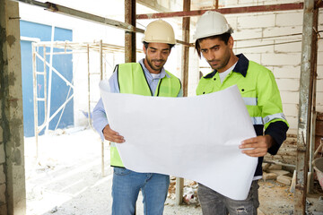 workers or architects holding and reading plan blueprint paper at construction site