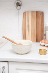 Home kitchen interior.Bowl with dough and spatula, eggs and bowl of sugar on kitchen table in modern kitchen.