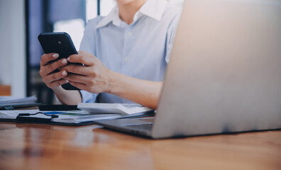 Portrait of a happy Asian businesswoman using mobile phone indoor, Asian businesswoman working in modern office.