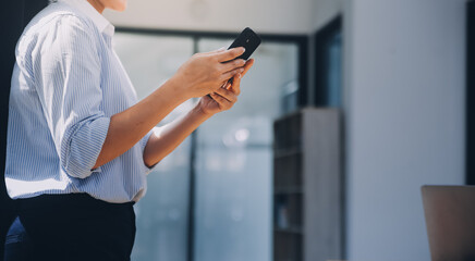 Portrait of a happy Asian businesswoman using mobile phone indoor, Asian businesswoman working in modern office.