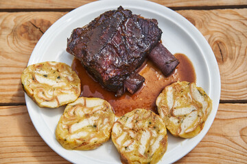 Top view on the plate with slowly roasted beef ribs in red wine and vegetables served with czech style bread dumplings from Carlsbad. Tender, juicy and delicious dish from cuisine of Czech Republic.