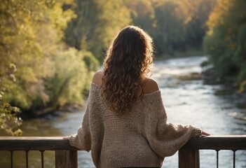 A woman stands at a railing, her back to the camera, as she overlooks a river view in a moment of peaceful reflection. - Powered by Adobe