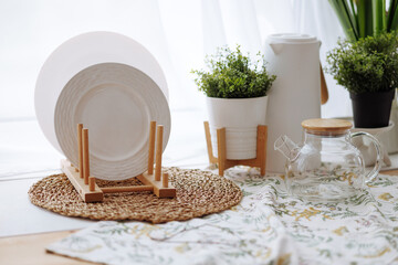 A white plate is on a wooden stand next to a potted plant. The scene is simple and clean, with a...