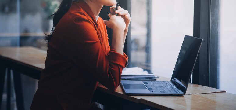 Asian Business woman using calculator and laptop for doing math finance on an office desk, tax, report, accounting, statistics, and analytical research concept