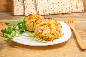 Chicken Vegetables Cutlets served with lettuce leaf, wooden cutlery, matzah piece on ceramic plate for Jewish holiday Pesach.