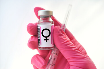 Pink gloved hand holding a vial with female symbol, hormones injections, concept hormone replacement therapy - obrazy, fototapety, plakaty