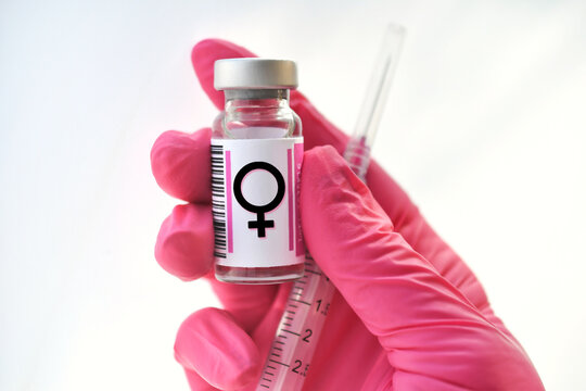 Pink gloved hand holding a vial with female symbol, hormones injections, concept hormone replacement therapy