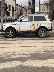 Old rusty white car standing on the street