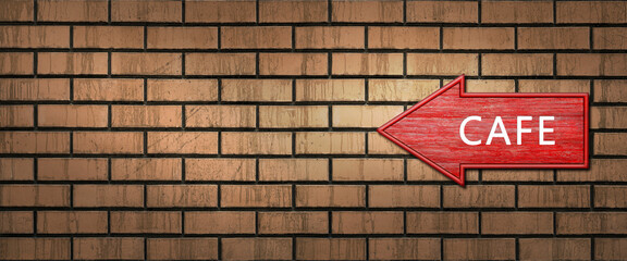 Red wooden shooter sign with the inscription CAFE hangs on a dark brick wall. Left arrow pointer