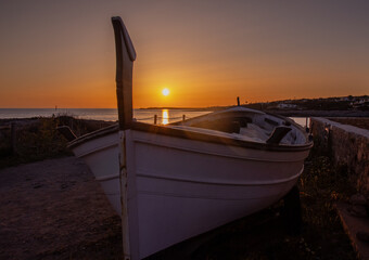 Spectacular sunset from Biniancolla cove, on the island of Menorca. A boat in the foreground, Spain