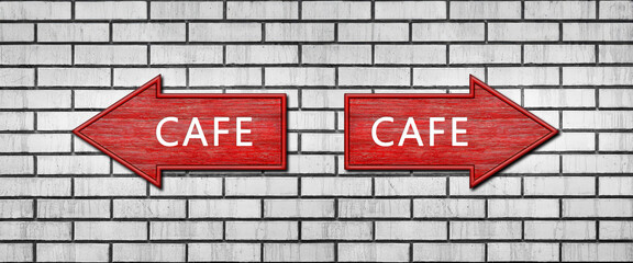 Red wooden arrow signs with the inscription CAFE hang on a white brick wall. Right and left arrow...