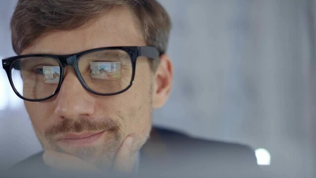 Businessman with glasses looking intently obscured partially by a translucent surface of laptop. Business concept