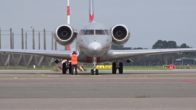 Private Business Corporate Executive Jet arriving at General Aviation Stands at airport with Marshaller