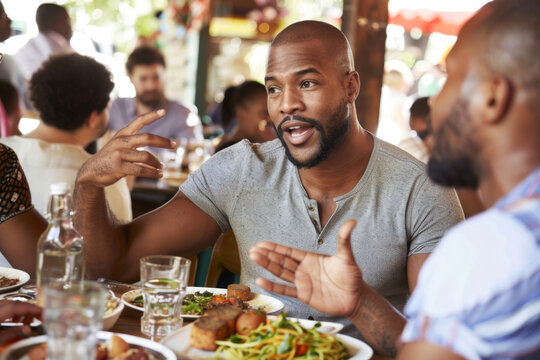 Happy diverse friends laughing at funny joke gather at table share lunch meal