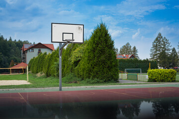 Boisko do gry w koszykówkę na świeżym powietrzu w otoczeniu zieleni z ciekawym odbiciem u spodu