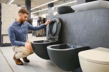 man chooses ceramic toilet bowl in a construction supermarket