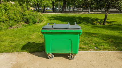Green waste container in a sunny park setting, depicting recycling and environmental conservation with urban park management  related to Earth Day and World Environment Day