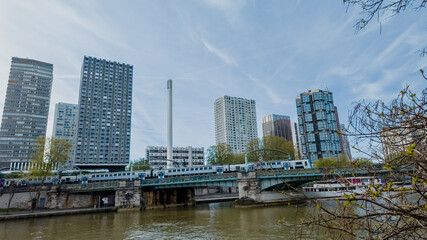 Urban skyline with modern high-rise buildings and a train crossing a bridge over a river, showcasing city transportation and architecture