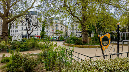 Tranquil urban park in spring with playground equipment and lush greenery, ideal for themes of city...