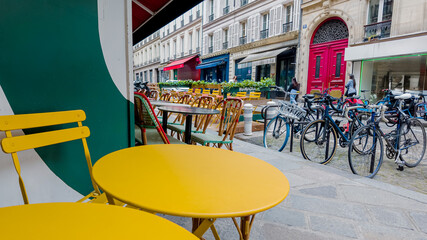 Paris, France, April 14th, 2024 Colorful sidewalk cafe setting with yellow tables and chairs on a...