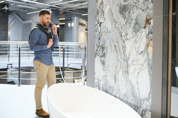 Young man choosing a bath and bath sink