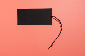 Black label with black cord with space for writing on a pink background. Black label on a pink...