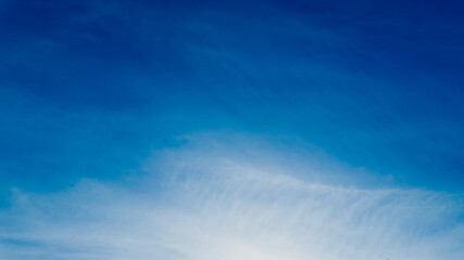 Serene blue sky with wispy clouds and a gentle sun, ideal for backgrounds, nature concepts, and...