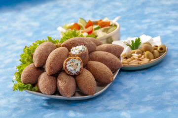 fried Arabic Lamb feta cheese Kibba with salad on a blue background