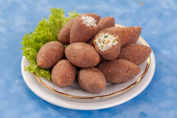 fried Arabic Lamb feta cheese Kibba with salad on a blue background