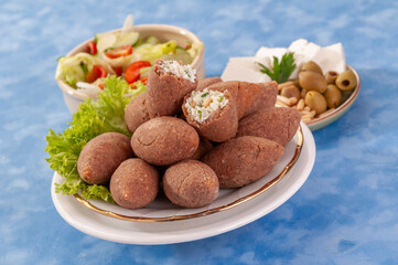 fried Arabic Lamb feta cheese Kibba with salad on a blue background