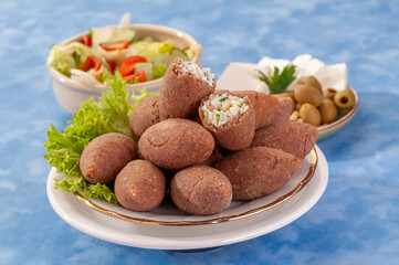 fried Arabic Lamb feta cheese Kibba with salad on a blue background