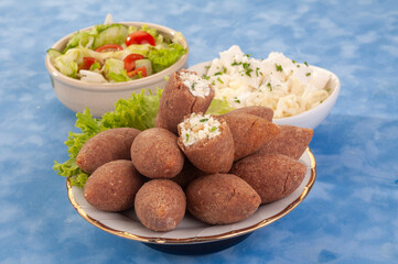 fried Arabic Lamb feta cheese Kibba with salad on a blue background