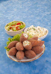 fried Arabic Lamb feta cheese Kibba with salad on a blue background