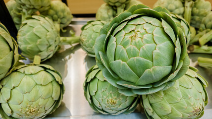 Fresh green globe artichokes on display at a vegetable market, ideal for healthy eating concepts and vegetarian recipe ingredients
