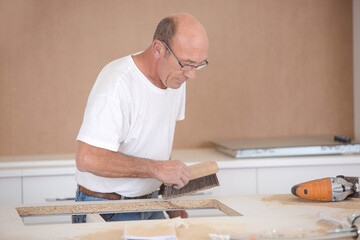 mature man driving nail into the wall to hang picture