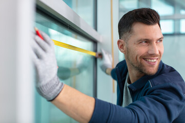 man using spirit level on window and looking over shoulder