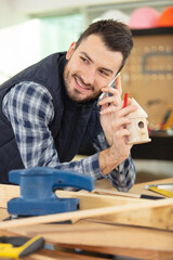 carpenter at workshop on the phone building birdhouse