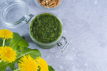 Creamy dandelion greens pesto in jar on a gray background, top view. Appetizer, condiment or topping. Healthy vegan food.