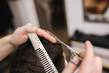 Man getting hair cut by scissor in barbershop. Barber use scissor. Professional barber work at home