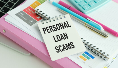 On a wooden table under a black paper clip lies a sheet of white paper with the text Personal Loan...