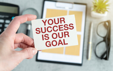 Your success is our goal text on blank business card being held by a woman's hand with blurred...