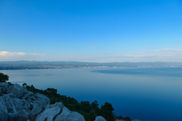 Panoramic view of the shore along Medveja, Croatia seen from a rocky hill above. The town is...