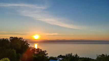 A panoramic view on the rising sun over the Mediterranean Sea in Croatia. The sky is orange and...