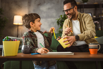 Father and son draw and paint together at home leisure activity