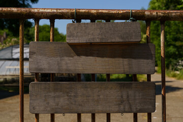 Blank Wooden Signboard Hanging on a Rusty Metal Fence