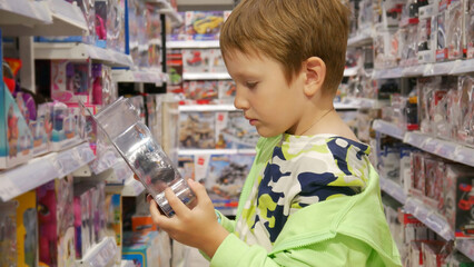 A cute boy examining a toy in his hands in a toy store