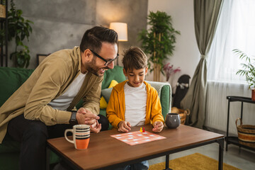 Father and son play board game together at home
