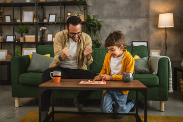Father and son play board game together at home