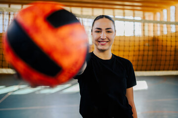 Portrait of a smiling young female volleyball player holding a ball in her hand